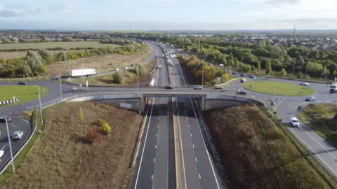 Ant Saddington/BBC An ariel view of the A421. The road is closed so has no traffic but it is clear of water. Other surrounding roads are busier.