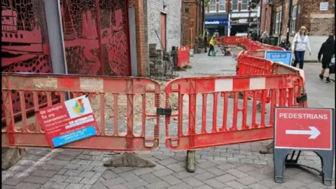 Goole Civic Society Red signs showing work being carried out on the pavement, with pedestrians being diverted past it.