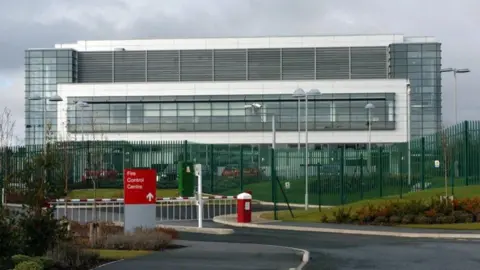 The former Wakefield Regional Fire Control Centre, a large glass building on a metal frame, with barriers across the entrance.