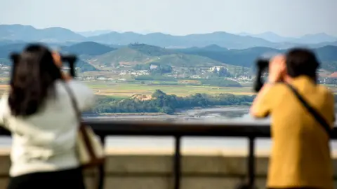 A man and a woman use binoculars to look at the North Korean side of the Demilitarised Zone dividing the two Koreas, from South Korea's Unification Observatory in Paju, north of Seoul.