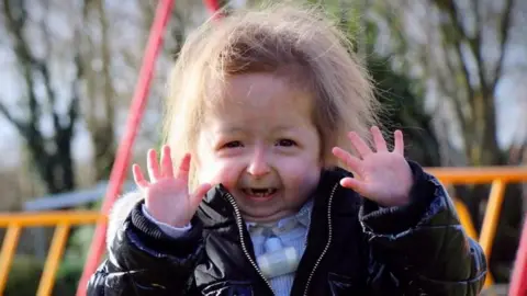 Isla looks at the camera for a photo and is wearing a black anorak and pale blue jumper