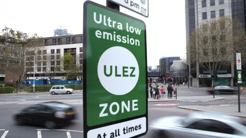 PA Media A sign saying Ultra low emissions zone infront of some passing cars