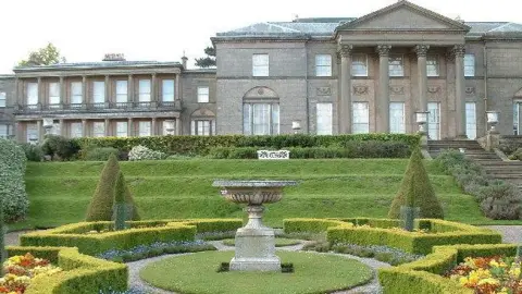 Rich Daley Plants and trees in a formally designed garden in front of the neo-classical facade and pillars of Tatton Hall mansion.