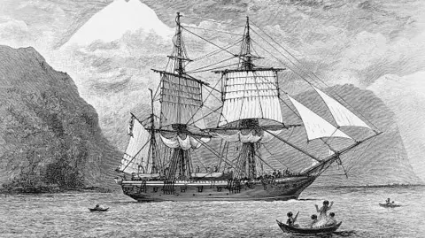 Getty Images A black and white illustration of the HMS Beagle in Straits of Magellan, dated 1890. Mountains can be seen in the distance and there are smaller boats nearby, with people on them.
