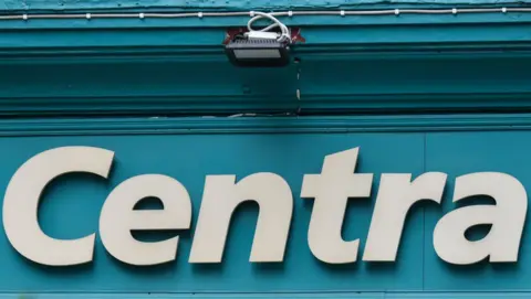 A shopfront sign reading "Centra" consisting of white letters on a teal background