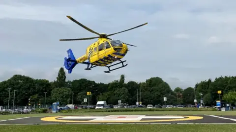 A yellow helicopter about to land at the hospital helipad