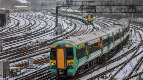 Getty Images Snow covered rail tracks on outskirts of Victoria Station in central London, with two green Southern trains approaching.