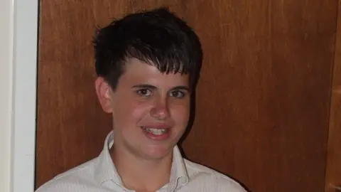 Jimmy Mizen wearing white shirt looking towards camera and smiling