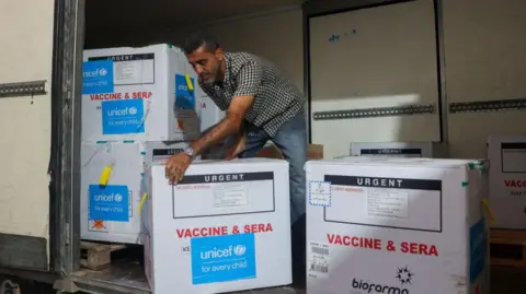 AFP A worker unloads a shipment of polio vaccines at a depot belonging to Gaza's health ministry on 25 August