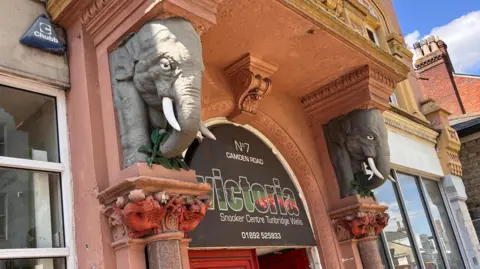 Two elephant head busts on either side of the door to Victoria Snooker Club in Tunbridge Wells