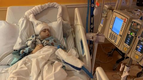 Caleb lying in a hospital bed