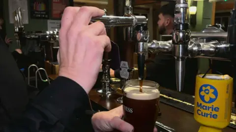 A glass of Guinness is poured in a pub bar