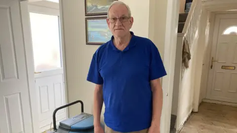 Fred Forth in his home alongside a dehumidifier