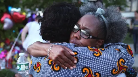 Mourners support each other while visiting a makeshift memorial outside of Tops market on May 15, 2022 in Buffalo, New York