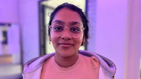BBC/Nicola Haseler Mansi Shah in a pink top and grey sweatshirt 