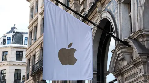 Getty Images Una bandera blanca con el logo de una manzana dorada cuelga de la fachada de piedra de la Apple Store.