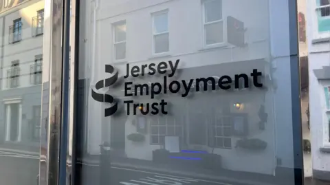 A glass door into a building. It says 'Jersey Employment Trust' in black writing.