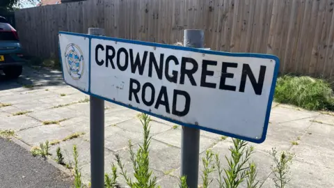 A sign bearing the worlds Crown Green road seen on sunny day.