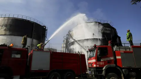 Reuters Firefighters put out a fire at a power station following an Israeli attack in Sanaa, Yemen (19 December 2024)