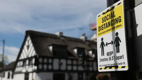 Reuters Social distance sign near Crown and Anchor pub