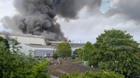 Industrial buildings with large clouds of smoke rising from them into the sky