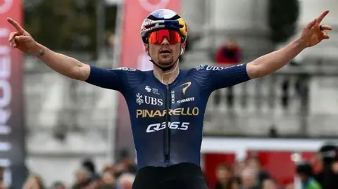 Tom Pidcock celebrates as he crosses the finish line to win the 2026 Milano-Torino race
