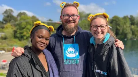 Sali Shobowale, Phil Mercer and Katherine Bett posing for the camera wearing dry robes and yellow Pudsey bear ears