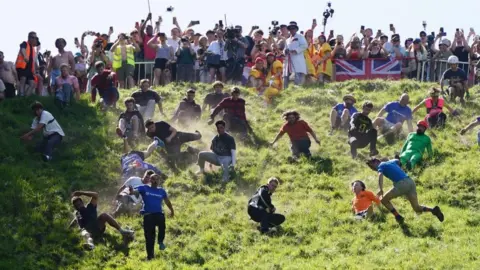 Participants take part in the first men's downhill race during the annual cheese rolling at Cooper's Hill in Brockworth, Gloucestershire.