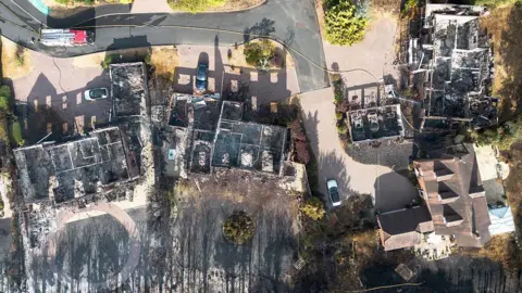 Ryan Jenkinson/Getty An aerial view of the remains of a home on Brunswick Gate following a huge fire in Stourbridge on August 14, 2026 in Stourbridge, England. During the UK's hottest day of the year, with temperatures soaring to 38.1°C, an extensive wildfire has spread to at least six homes on the edge of the golf course in Stourbridge prompting mass evacuations and leaving two people suffering from heat and smoke inhalation. The image shows a series of burned out houses