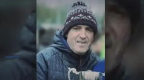 RTÉ George Turner, a man in a wooly hat and coat. He holds a trophy.