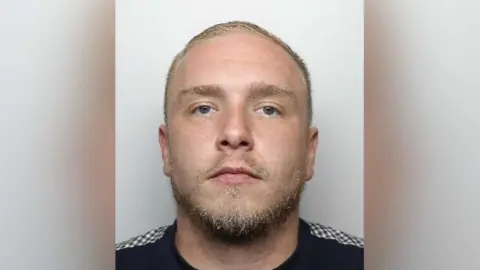 South Yorkshire Police A mugshot of Shaw who has blond, very short, hair and a beard. He appears to be wearing a black top with a chequered pattern on his shoulder.