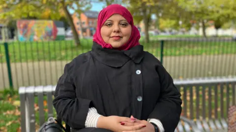 Shaista Aziz sits on a bench in a park just off Cowley Road in Oxford. 