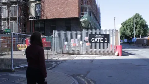 BBC A woman looks at the Ordsall Lane Legacie building site