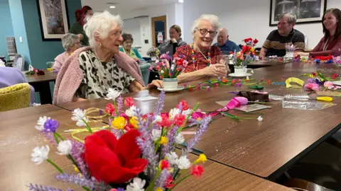 Residents sitting at a table arranging flowers