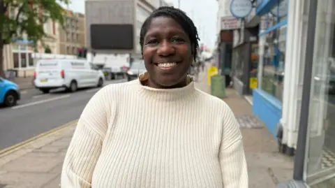 Dorothy Koomson stands on the street smiling for the camera.