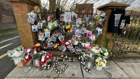 Floral tributes and candles placed on a railing at the corner of Back Falkner Street South. 