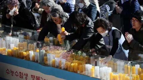 Reuters Parents light up candles at a Buddhist temple in Seoul as they pray for their children, who are taking the high-stakes Suneung exam on 13 November