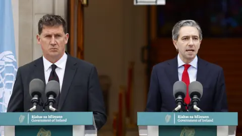 Shutterstock Eamon Ryan and Simon Harris stand behind the podium outside Government House in Dublin