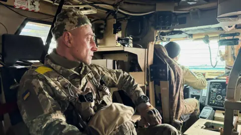 A Ukrainian soldier in a military vehicle 