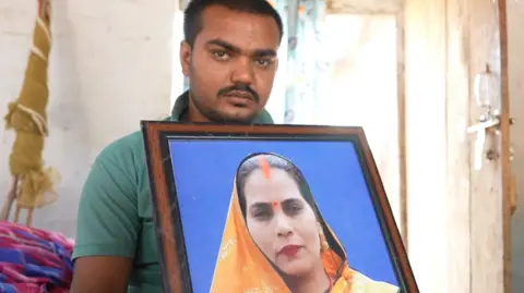 Sunny Pandey holds a picture of his mother Meena who was killed in the crush
