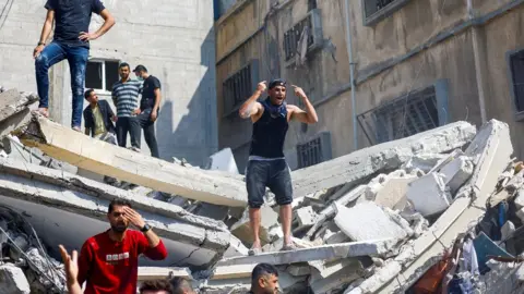 Reuters Palestinians search for casualties at the scene of an Israeli strike in Khan Younis, in the southern Gaza Strip (24 October 2023)