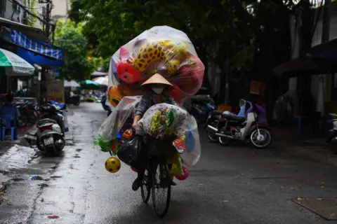 Getty Images Trader on a bicycle with wares protected against the rain