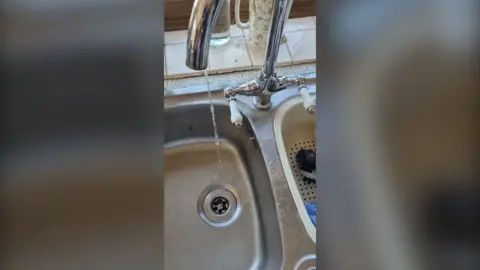 An image of a sink with water dribbling from a tap