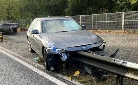 Image of a crashed BMW car mangled front in a crash barrier on the road