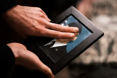 Jared Stapp Max using his fingers to conceal his face on a photograph of himself as an airman