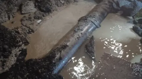 Scottish Water A large pipe underground submerged in muddy water