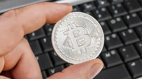 Getty Images Man's hand holding 'bitcoin' over laptop keyboard