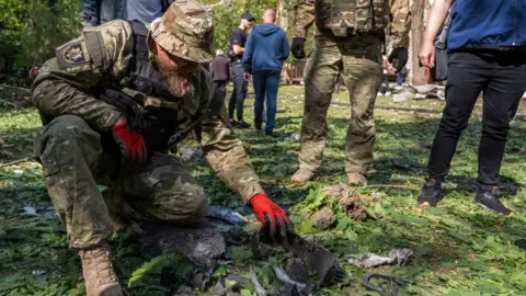 UA:PBC"/Global Images Ukraine   A military expert examines a bomb's fragments collected at the site of a Russian aerial bombing in the Shevchenkivskyi district on May 5, 2024 in Kharkiv, Ukraine