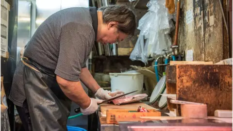 Getty Images A man slices tuna at Tsujiki market
