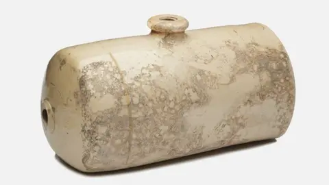 Mola Image of a cream-coloured cylindrical ceramic hot water bottle with two bung holes